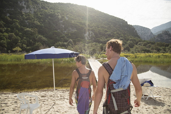 意大利撒丁岛卡拉露娜海滩上携带背包的青年男子图片