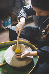 年轻女人在陶瓷轮上做瓷器图片