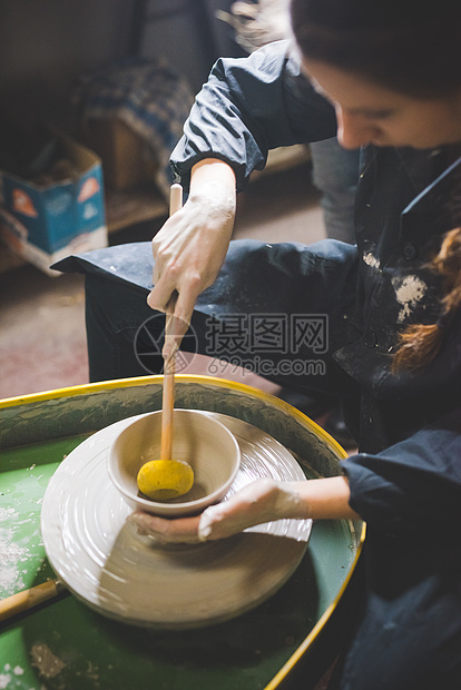 年轻女人在陶瓷轮上做瓷器图片