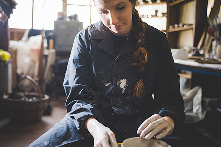 年轻女人在陶瓷轮上做瓷器图片
