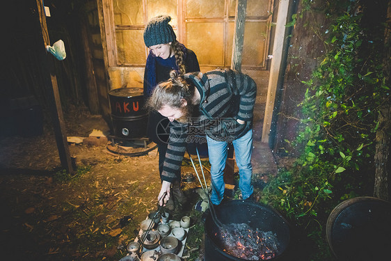 一对夫妇微笑着用夹子从火中取出粘土锅图片