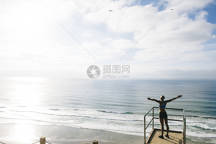 站在海边的年轻女子举起手臂图片