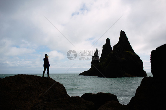 成年女子站在岩石上看着海图片