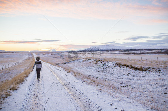 冰岛在雪覆盖的乡村公路上行走的妇女图片