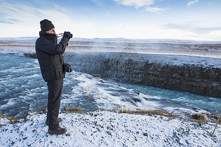 拍摄位于冰岛西南部赫维塔河峡谷中的格尔福斯瀑布的资深男子图片