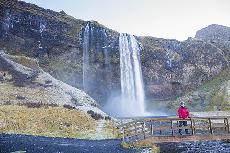 站在桥上看着风景站在她身后的Seljalandsfos瀑布冰岛西南图片