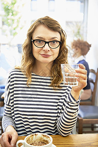 咖啡馆中女人端着水杯看镜头图片