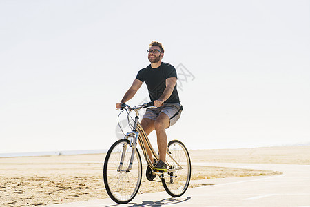 在海滩上骑自行车的年轻人图片