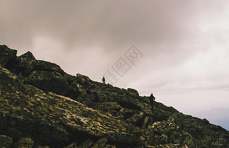 俄罗斯乌拉尔山两名男子在崎岖的岩石上徒步旅行的剪影图片