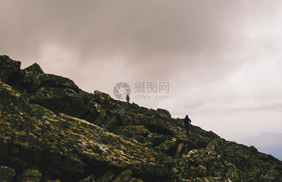 俄罗斯乌拉尔山两名男子在崎岖的岩石上徒步旅行的剪影图片