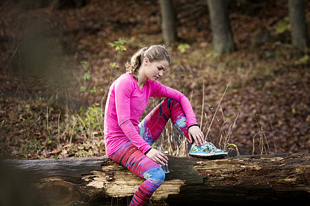 身着运动服装坐在秋树上向下看的年轻女子图片