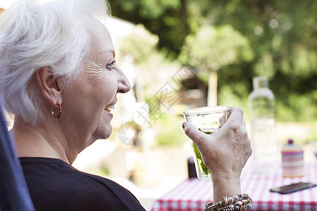 年长女人在花园里放松喝着冷饮图片