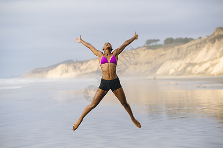 穿比基尼的女人在海滩上跳跃图片