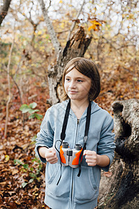 年轻女孩在森林里手拿双筒望远镜图片