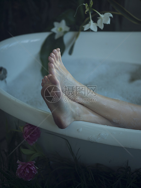 坐在浴缸的年轻女子脚在浴缸的边缘图片