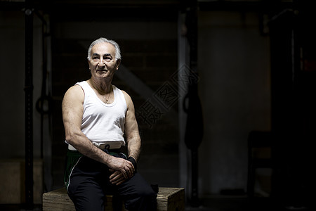 坐在黑暗健身房里的老人肖像图片
