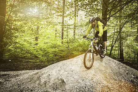 成熟的男山上骑自行车过森林中的山丘图片