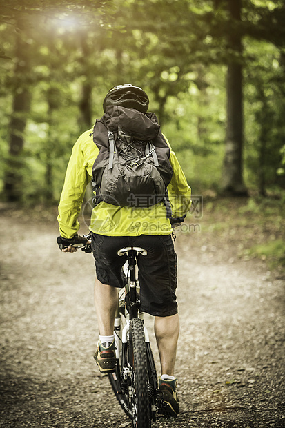 在森林中骑自行车的成年男山上骑自行车者的近视图片