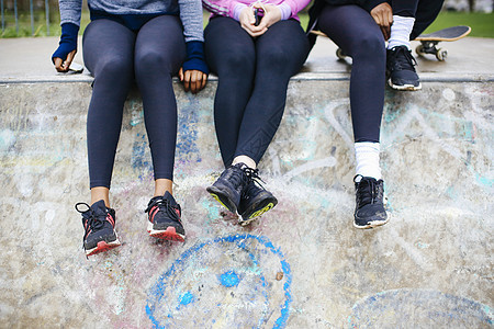 坐在滑板公园的三名年轻女滑板运动员图片