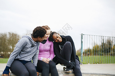 三名在滑板公园闲谈的年轻女滑板运动员图片