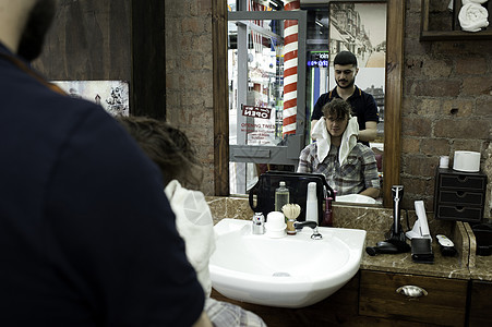 理发店年轻男子和理发师的镜像形象图片