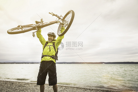 成熟的男山上骑自行车在湖边着自行车图片