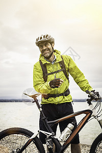 湖边成年男山上骑自行车者的肖像图片