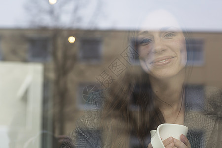 年轻女透过咖啡店窗口看的肖像图片