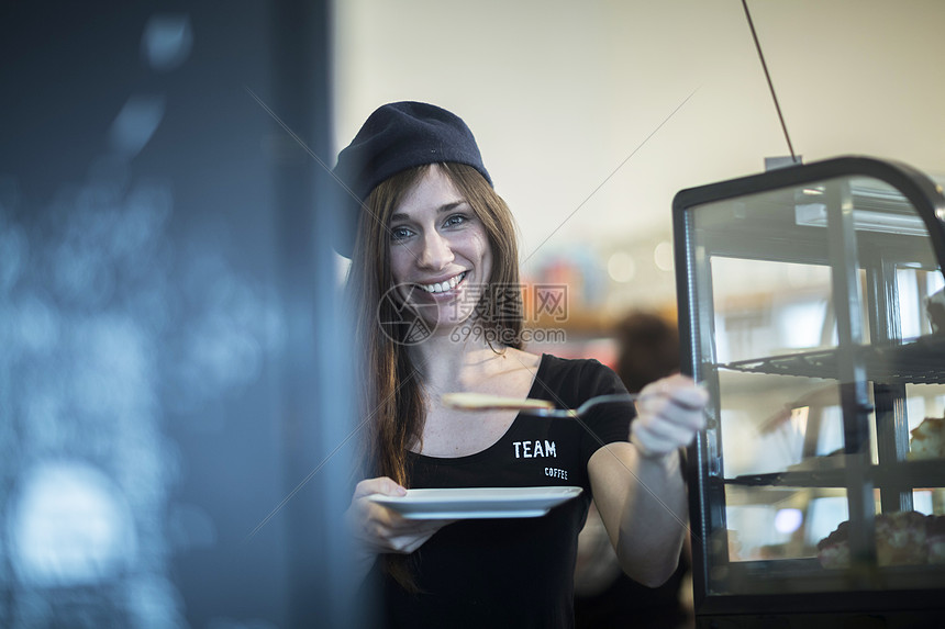 年轻女服务员在咖啡馆拿着盘子和蛋糕片的肖像图片