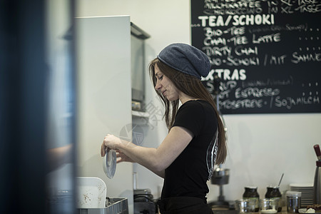 在咖啡厅厨房工作的年轻女服务员图片
