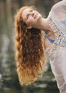 清静的年轻女子肖像长红发从河边凝视着图片