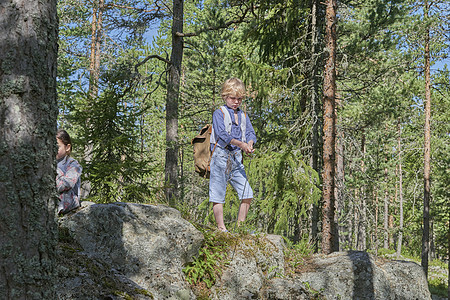 男孩在森林中的岩石上穿旧衣服图片