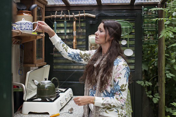 年轻妇女在露天小屋厨房准备茶叶图片