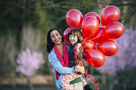 年轻女人和女儿拿着红气球逛公园图片