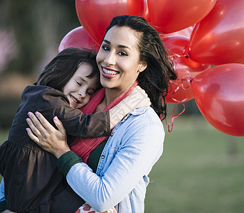 在公园里妈妈抱着拿着红色气球女孩图片