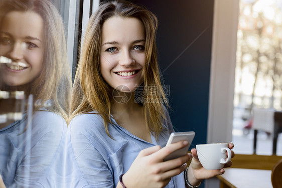 年轻女子拿着咖啡杯和智能手机图片