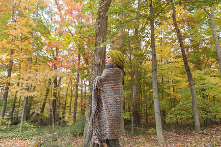 成年女性围着披肩站立在秋天的森林中图片
