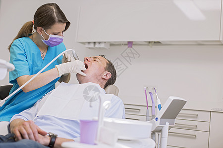 对成年男子进行牙科检查的医生图片