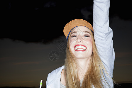 身戴棒球帽的年轻女子微笑着抬起手图片