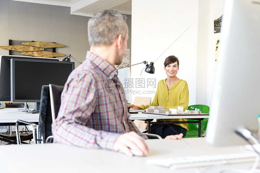 用计算机的男人回头和微笑的女人说话图片