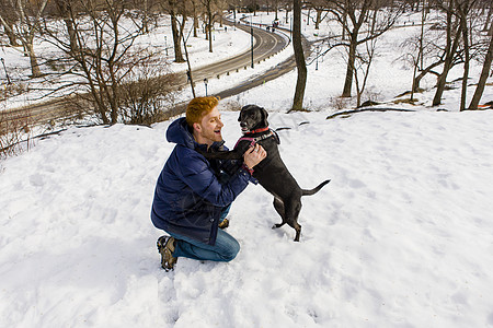 雪地上一名年轻男子抱着爱犬图片