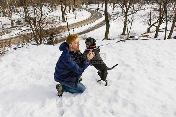 雪地上一名年轻男子抱着爱犬图片