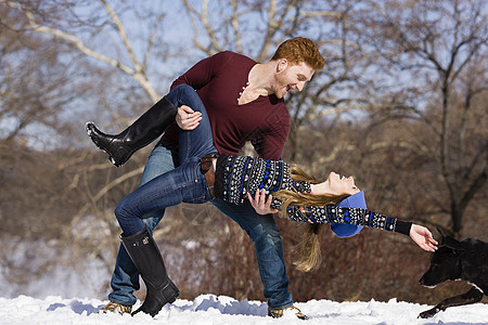 在公园雪地里玩耍的年轻夫妇图片