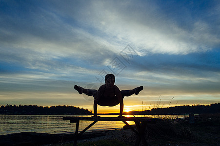 日落时在湖边做瑜伽的女性剪影图片