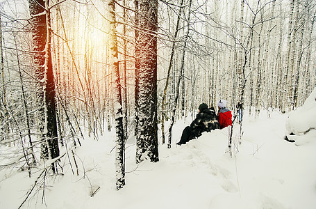 一对夫妇坐在雪森林里看着日落图片