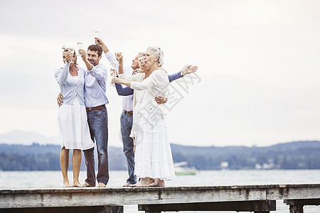 一群朋友站在码头拿着酒杯庆祝图片