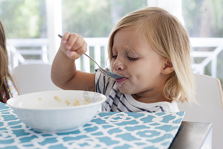女孩用勺子碗吃早餐背景图片
