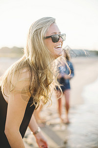 戴墨镜的金发美女在海滩大笑图片