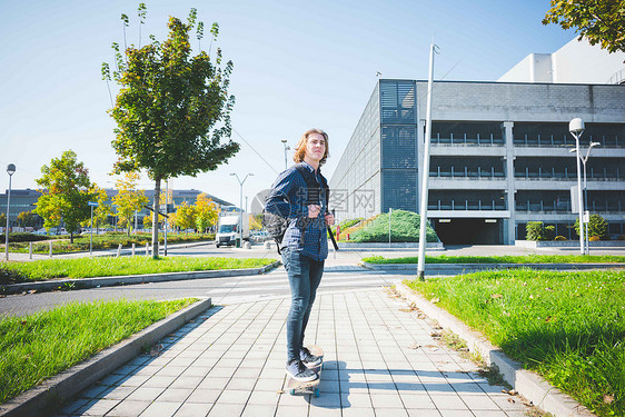 年轻男城市滑板运动员在人行道上滑滑板图片