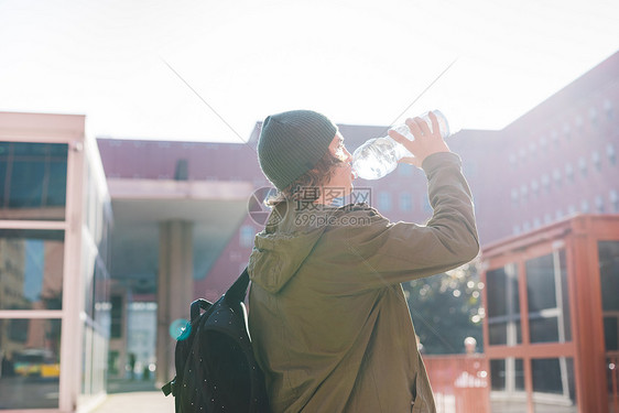 喝瓶装水的城市青年男子图片